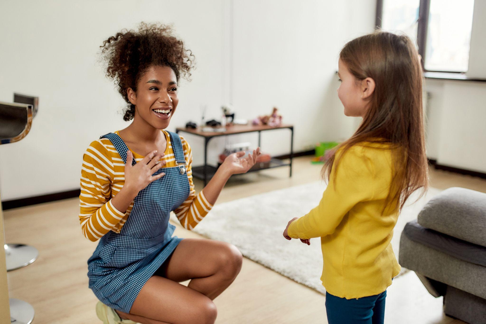 A childcare professional talking with a young child at home